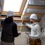 Un intérieur de maison en pleine "rénovation maison" avec des outils, des matériaux de construction et des bâches de protection, sous une lumière naturelle